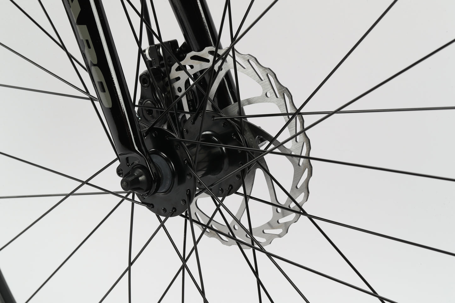 Close-up of the Beasley 27.5s wheel highlights its mechanical disc brakes and spokes. The black fork and hub accentuate the brake system against a neutral backdrop, perfectly complementing Haro MTBs lightweight aluminum frame.