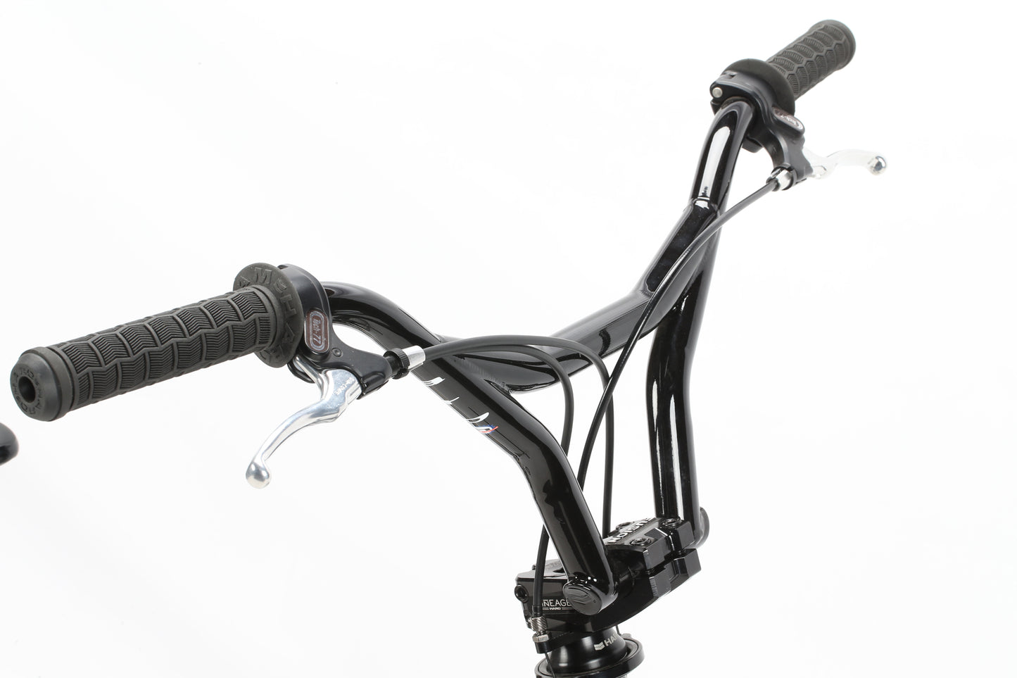 Close-up of the Haro Bikes Lineage Ground Master 26 2023 black BMX handlebar with rubber grips and brake levers on a white background, highlighting its robust chromoly frame.