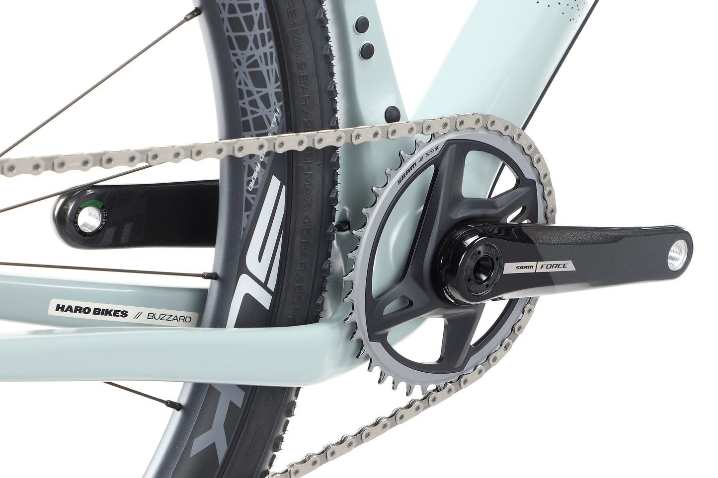 Close-up of a bicycle crankset labeled Haro Bikes and Buzzard Carbon Top Shelf, ideal for bikepacking on gravel roads.