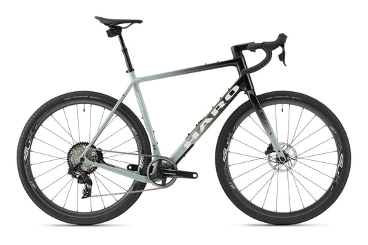 The Buzzard Carbon Top Shelf is a sleek gravel bike with a gray/black frame, drop handlebars, and disc brakes for bikepacking adventures.