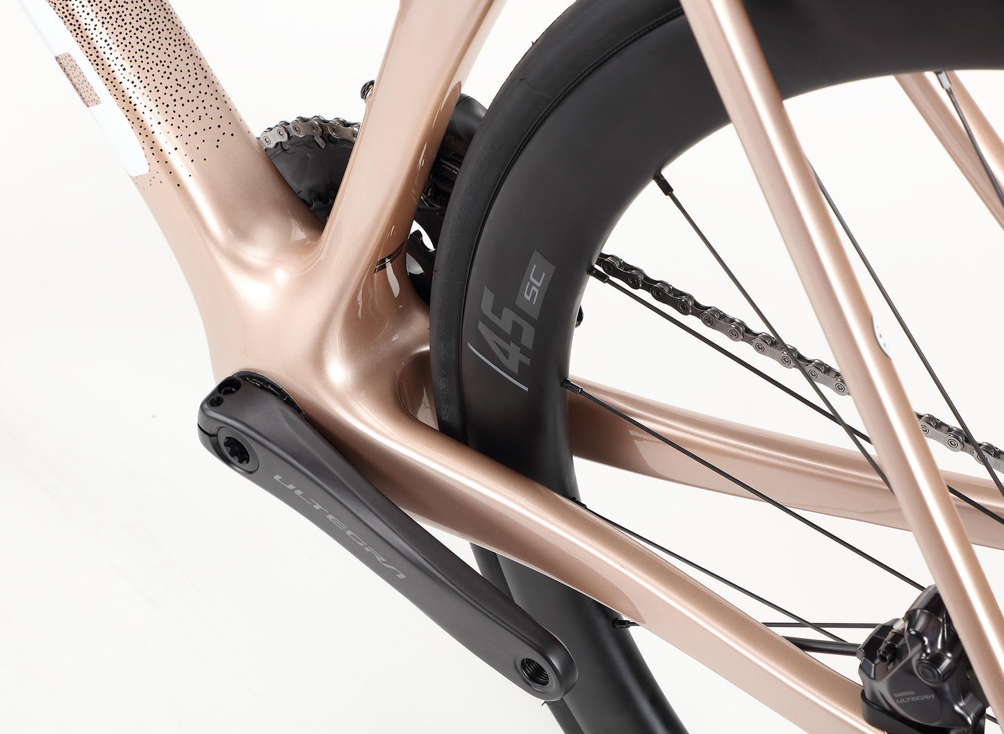 Close-up of the sleek Rivette Carbon 1 bicycle frame by Haro Bikes in metallic pink, highlighting carbon fiber detailing near the crank and rear wheel. Black spokes and rubber wheels complement this race-ready design.