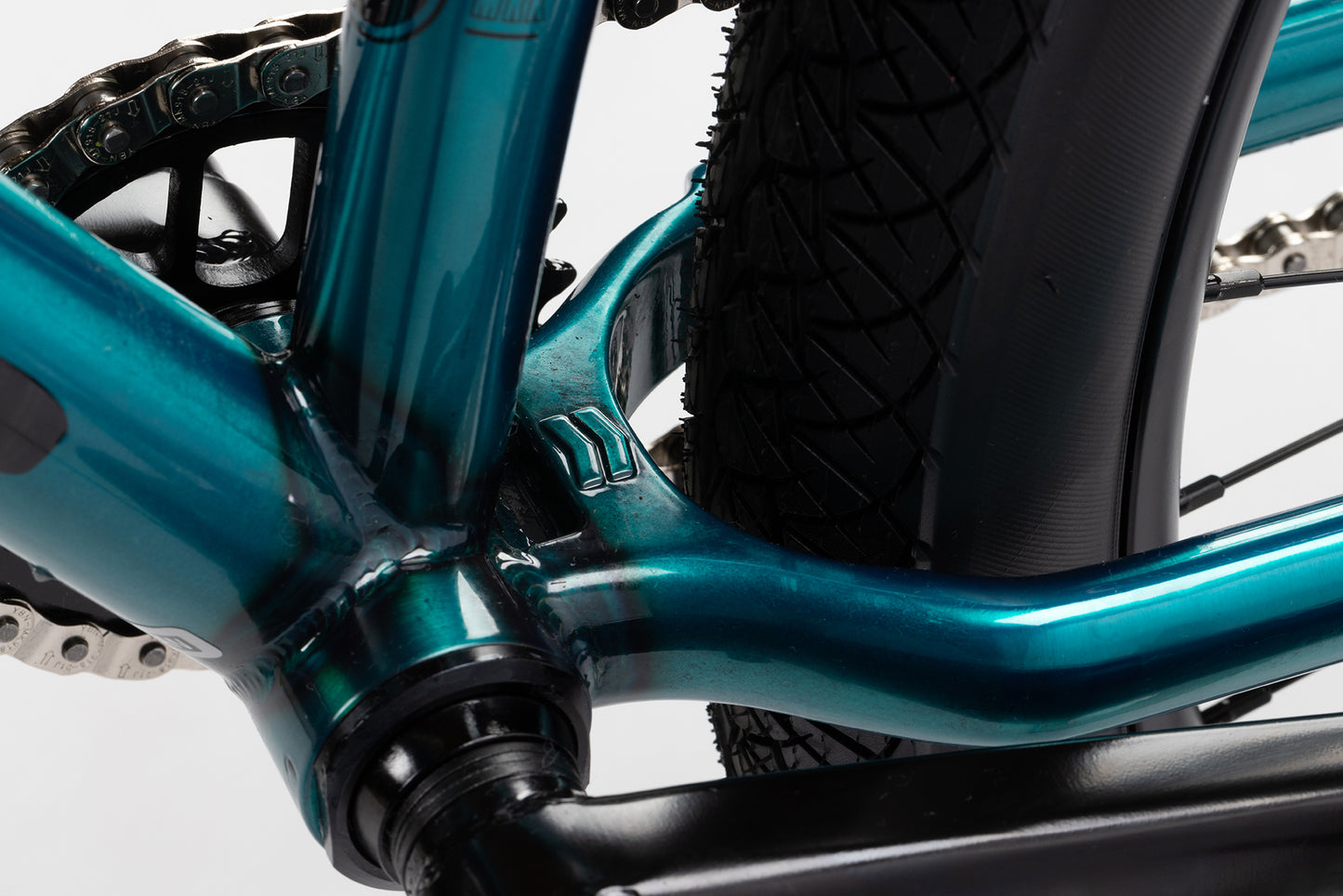 Close-up of the Steel Reserve 3s metallic blue chromoly frame near the rear wheel, highlighting the chain, tire tread, and gears.