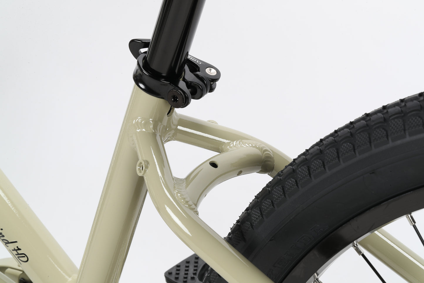 A close-up of the Tradewind HD by Haro Bikes showcases its beige, rust-resistant aluminum frame contrasting with the black seat post and clamp. The rugged tread pattern on the thick rear tire highlights the detailed design and construction of this bikes rear section.