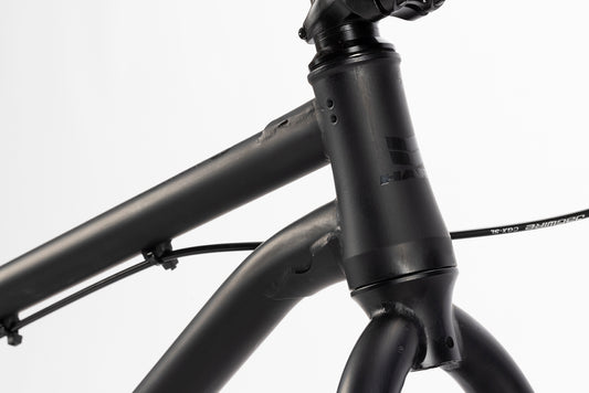 Close-up of the Steel Reserve 1 frame in matte black, featuring BMX-style head tube, handlebars, and brake cable.