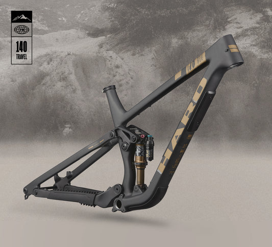 Daley Carbon Frameset in matte black with tan accents, shown upright against a gray, rocky backdrop.