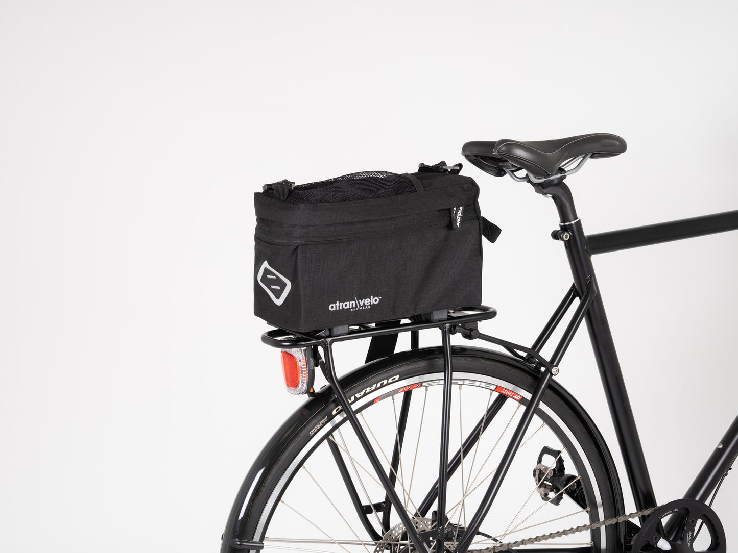 A black bicycle with a rear rack carrying the ZAP EASY Top Bag by Atran Velo features a smooth, minimalist design complemented by a red and white rear tire. This water-resistant setup enhances its sleek look against the plain white background.