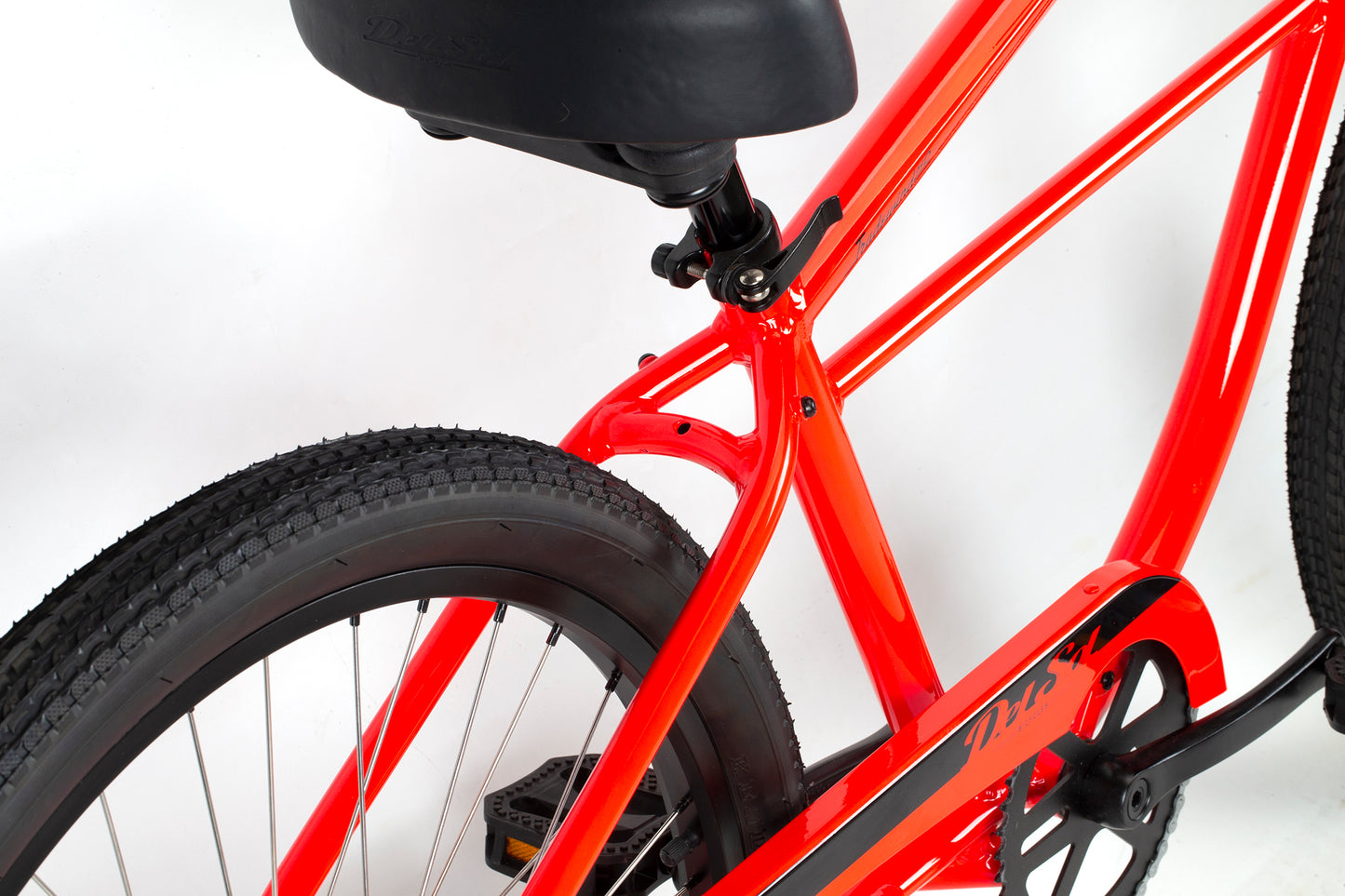 A close-up of the bright red Tradewind HD bicycle frame by Del Sol features a black seat and tire, highlighting the rust-resistant seat post, rear wheel, and part of the chain guard against a white background, showcasing its durability and vibrant color.