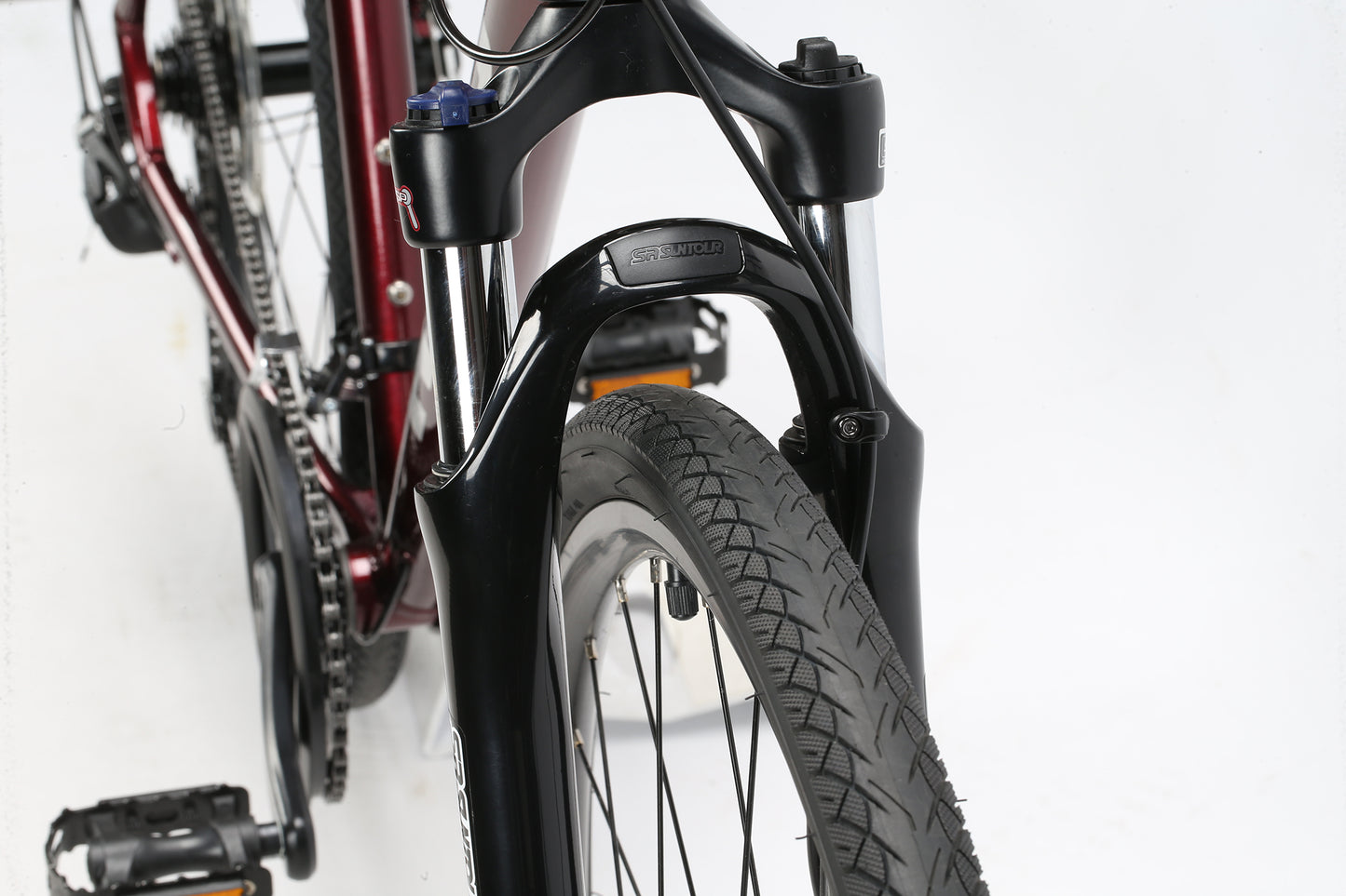 Close-up of the Bridgeport MicroShifts front wheel and suspension fork by Haro MTB. The black fork and tire tread are sharp, with a maroon frame partially visible against a white backdrop.