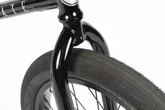 Close-up of the Haro Bikes Interstate Matte Black/Gloss Black BMXs front wheel and fork, showcasing the tread pattern and the glossy chromoly frame finish. Sealed bearings promise a smooth ride, all set against a plain white background.