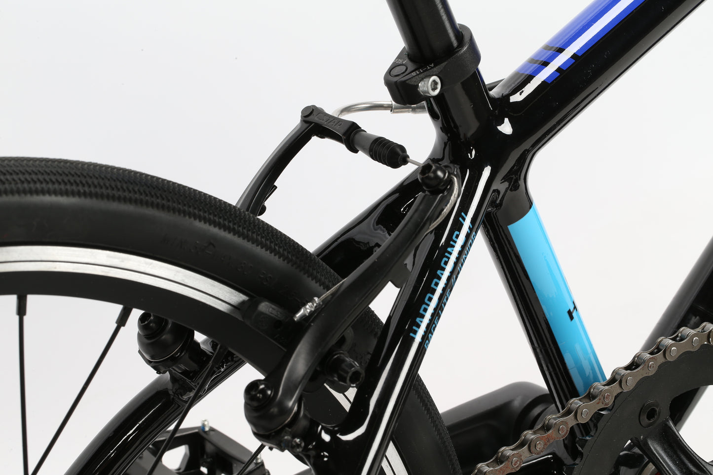 Close-up of the black and blue Haro Bikes Junior bicycles rear wheel, chain, and brake. Focus is on the brake mechanism and 6061 alloy frame details, with visible tire tread and part of the robust frame.