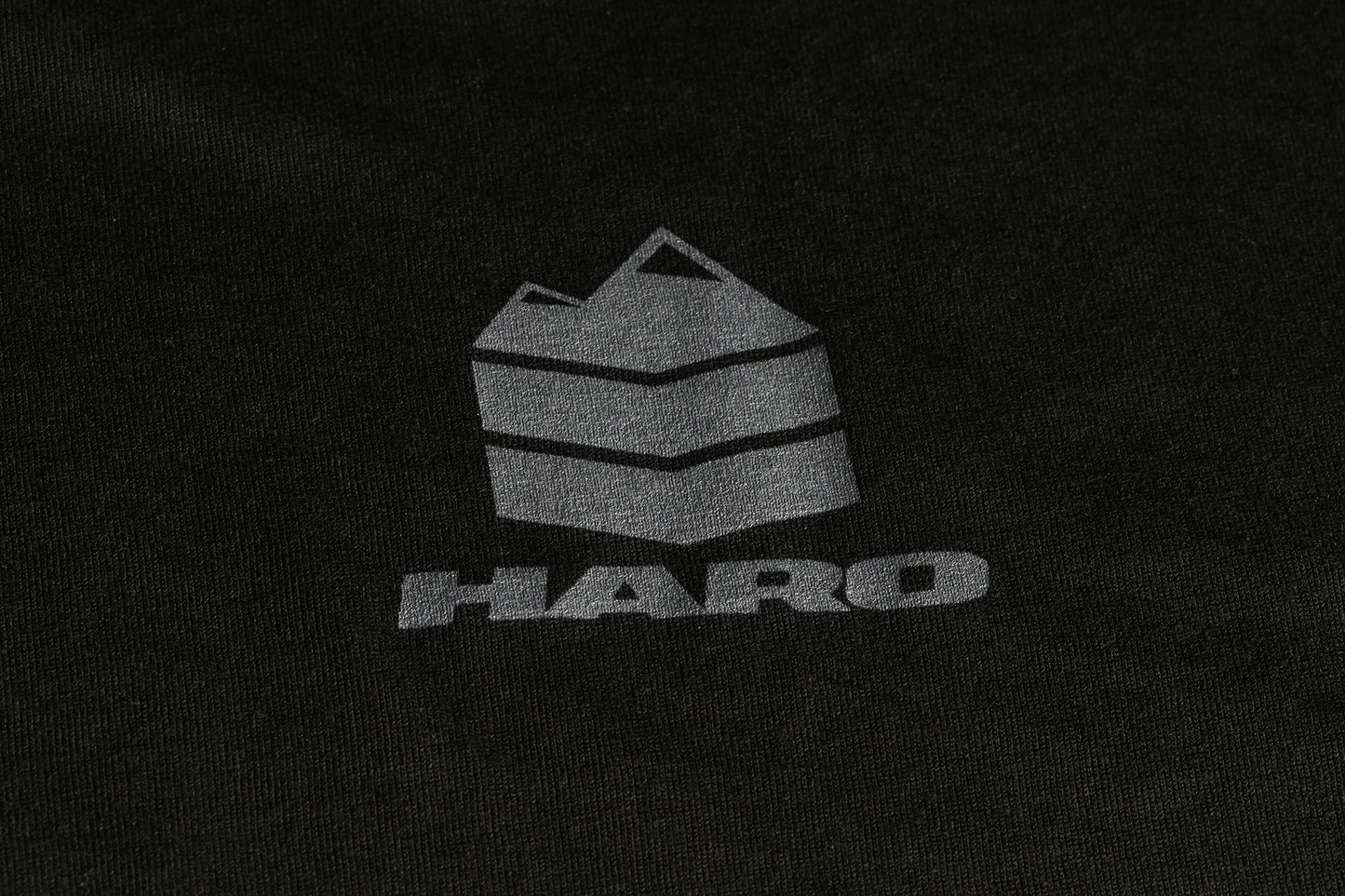 The Haro MTB DryBlend Shirt by Haro Bikes features a dark fabric with a geometric mountain logo and bold HARO text.