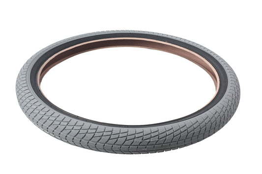 The Haro Bikes Downtown Tire Grey/Black features a textured tread for excellent traction and highlights its stylish reddish-brown inner rim on a white background. Ideal for urban cycling, this entry-level tire is available in multiple sizes to meet diverse needs.