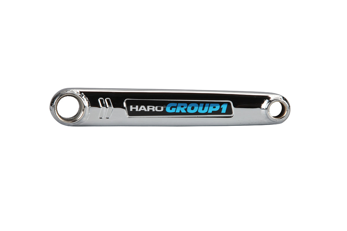 Close-up of a shiny, metallic object featuring Lineage Group 1 in blue and black text. It resembles a component from Haro Bikes Lineage Cranks with chromoly crank arms and holes at both ends, set against a plain white background.