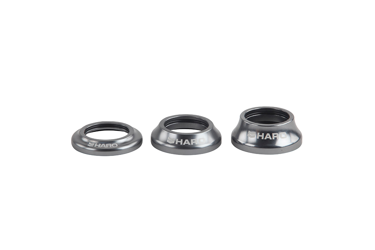 Three metallic conical objects of varying sizes are lined up horizontally, each labeled Integrated Headset by Haro Bikes. The shapes resemble Campy style spacers or washers with a central hole and appear to be made of steel or aluminum.