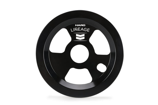The Lineage Grind Disc by Haro Bikes is a black circular bike sprocket with Haro and Lineage engraved, featuring a central hole and three smaller triangular holes. It also serves as a grind disc guard for protection during intense grinding sessions.
