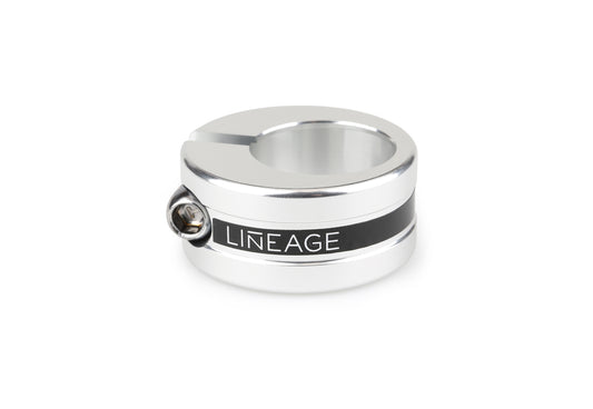 The silver Haro Bikes Lineage Seatpost Clamp features LINEAGE engraved on a black band, CNC machined from 6061 aluminum. A side screw is visible, and it boasts a sleek cylindrical shape with a smooth metallic finish.