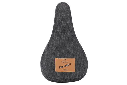 The Premium Denim Stealth Seat, by Premium, features a sleek gray denim-style design with a leather patch inscribed Premium at the center bottom.