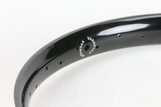 Close-up of a black Varanyak 36H rim by Premium, with VARAN in white. Designed for ultra-technical riding, it features several spoke holes to maintain low PSI. Set against a plain white background.