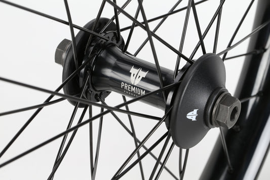 Close-up of a Curb Cutter Front Wheel hub with black spokes. The Premium hub features a stylized Team logo against a plain white background, emphasizing its sleek and modern design.