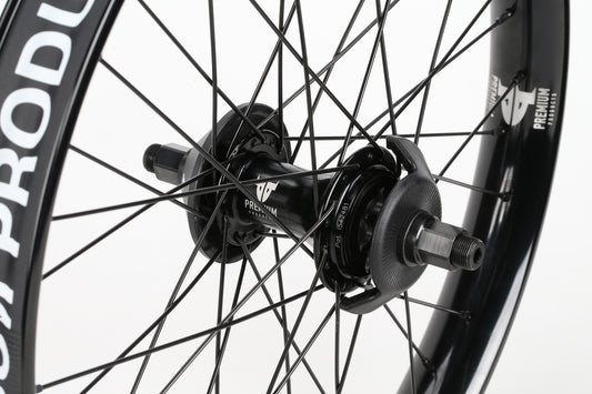 Close-up of the Curb Cutter Planetary Rear Wheel by Premium, showcasing its black spokes and PREMIUM branded hub against a white backdrop. Partially visible rim hints at its wide width, ensuring stability and enhanced performance.