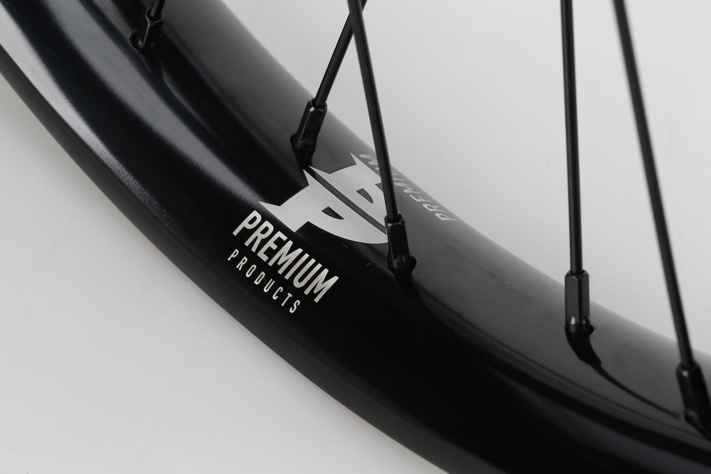 Close-up of the Premium Curb Cutter Front Wheels black rim and spokes, featuring the Premium logo in white. The image spotlights the Varanyak rim section and spokes, offering a sleek design for performance enthusiasts.