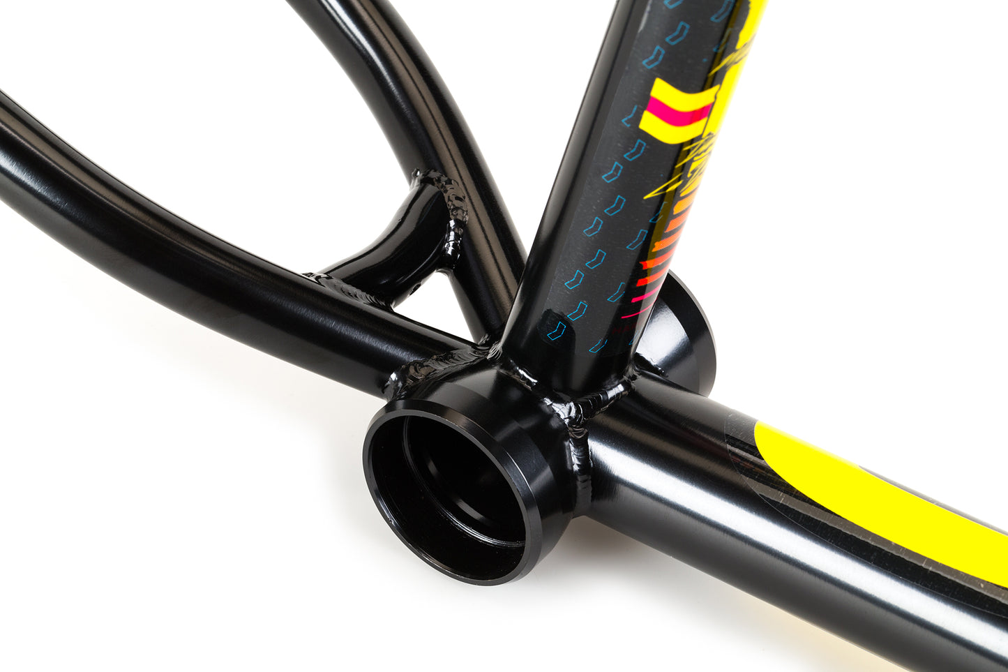 The La Bastille v2 Frame by Haro Bikes features a close-up of its black frame with colorful blue, yellow, and red geometric designs. Ideal for flatland riding, it has visible welds and a hollow bottom bracket for strength and durability, inspired by Matthias Dandois freestyle performance.