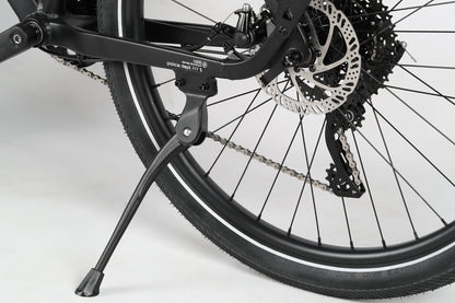 The PD1 27.5 by Haro MTB is shown from the rear, highlighting its kickstand, rear wheel with disc brake and gears, chain section, and a tire with a reflective strip against a plain white background.