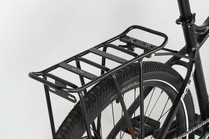 Close-up of the Haro MTB PD2 27.5s rear tire, featuring a metal luggage rack with multiple horizontal bars attached above it and supported by a sturdy Suntour fork, all set against a plain white background that enhances the bikes refined design.