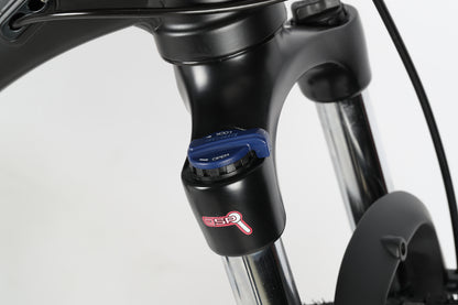 Close-up of a black Suntour fork with a blue lockout lever, featuring the DSP logo on the Haro MTB PD2 27.5. The shiny metal stanchions complement the tapered head tube, all set against a plain white background.