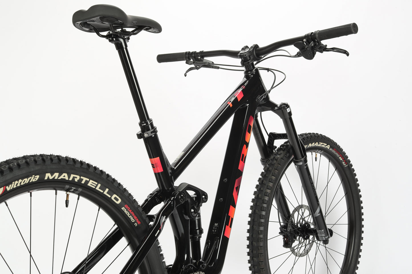 Against a white background, the Daley Alloy 2 from Haro MTB is a sleek black mountain bike with red accents and thick tires. It features an aluminum frame, straight handlebar, and cushioned seat, ideal for off-road cycling. This all-mountain 29er offers unmatched performance.