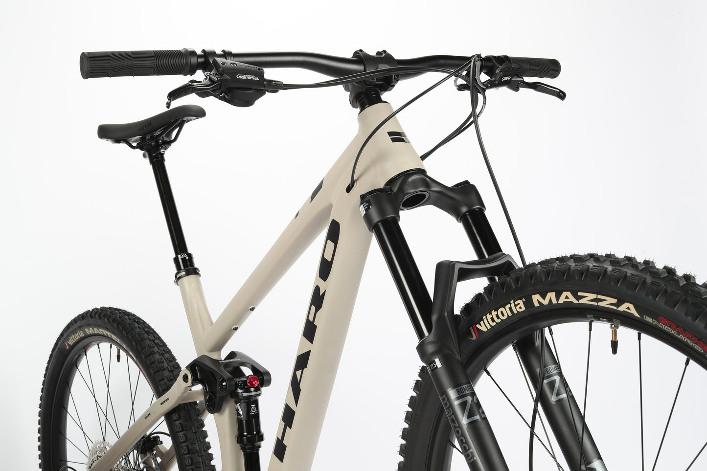 Close-up of a Haro MTB Daley Alloy 2, an all-mountain beige 29er bike against a white background. It features Vittoria Mazza tires, front suspension fork, aluminum frame with Haro branding, and black handlebars and seat.