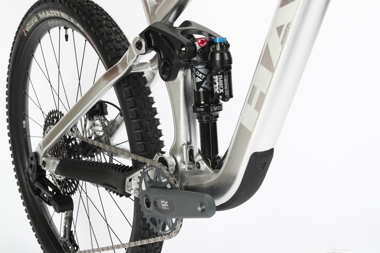 Close-up of the Daley Alloy LTD 1s rear suspension system, showcasing the black and blue Fox Float X2 shock absorber. The silver Haro MTB frame, chainring, and rear tire stand out against a plain white background.