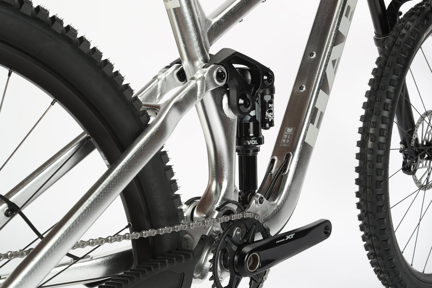 Close-up of the limited edition Daley Alloy LTD 2s rear suspension and drivetrain, showcasing its silver metallic Haro MTB frame, central Fox coil shock absorber, black crank arm, and chain on a gear sprocket.