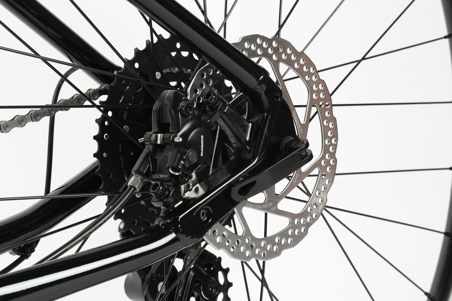 Close-up view of the Haro MTB Flightline LTD 29s rear disc brake and gear system with Tektro hydraulic brakes, highlighting the metal rotor and black components. Detailed Shimano Cues, spokes, and chain are visible against a white background.