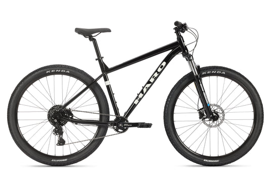 The black Flightline LTD 29 mountain bike from Haro MTB features a sleek frame, Shimano Cues, Kenda tires, Tektro hydraulic brakes, and a front suspension fork for off-road cycling.