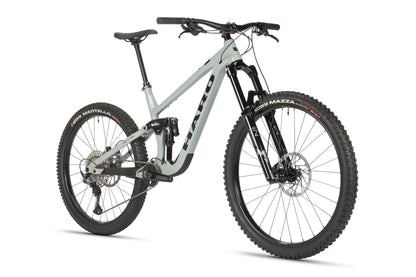 A light gray mountain bike with a performance alloy frame and thick black tires features a suspension fork. The Haro MTB branding graces the frame of the Greer Alloy 2 model, offering wide handlebars with gear shifters and brakes against a plain white background.