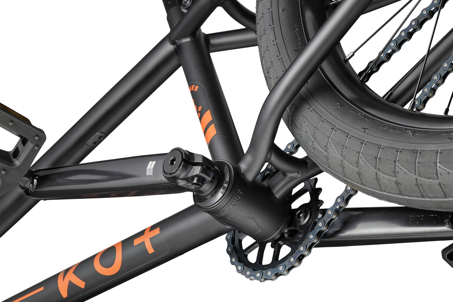 Close-up of a Burgess BMX bike crank, pedal, and chainring—made for versatile performance, featuring orange lettering on the frame.