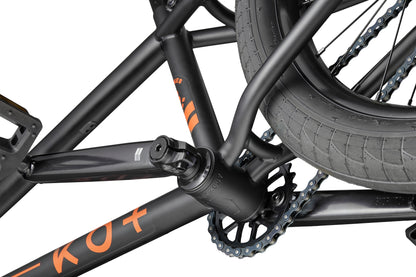 Close-up of a Burgess BMX bike crank, pedal, and chainring—made for versatile performance, featuring orange lettering on the frame.