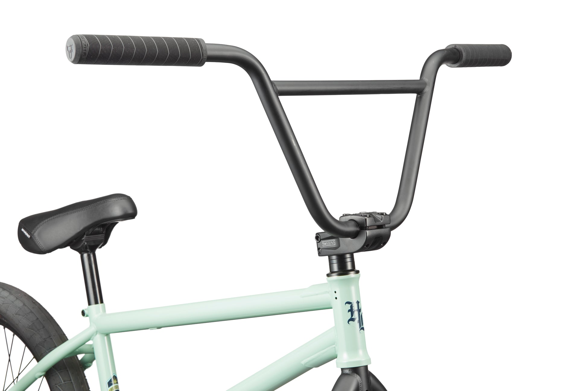 Close-up of the Burgess BMX bike’s handlebars, seat, and frame; its light green body and black handlebars stand out.