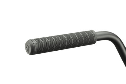Close-up of a black, textured handlebar grip with horizontal grooves on a Clairemont BMX bike’s curved metal handlebar.