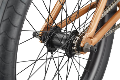 Close-up of Dana's rear wheel hub, spokes, chain, and tire, featuring a metallic bronze frame for pro-level street performance.