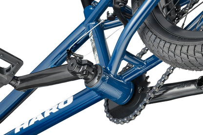 Close-up of a blue Downtown 16 BMX crankset, pedal, and chain, showing frame details and rear tire.
