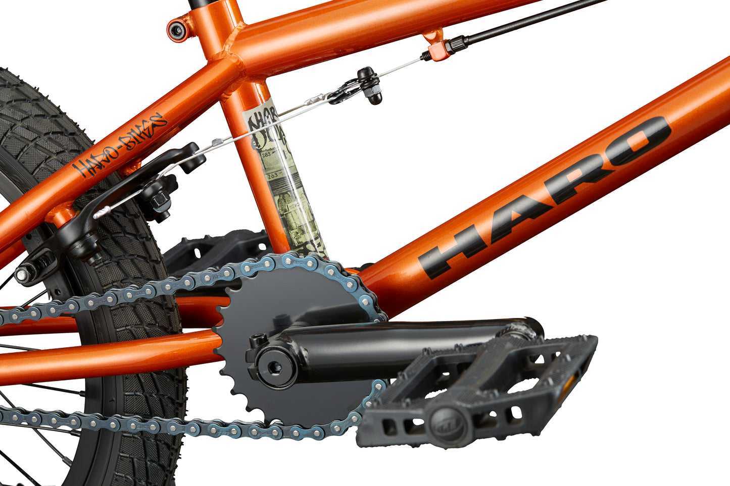 Close-up of the Downtown 16 BMX bike in orange, highlighting the pedals, crankset, rear wheel, and frame details.
