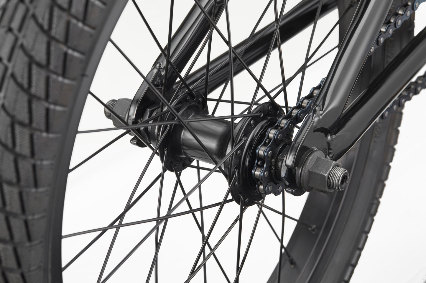 Close-up of Downtown 18 BMX wheel—black spokes, hub, chain, and tread—ideal for young riders against a white background.