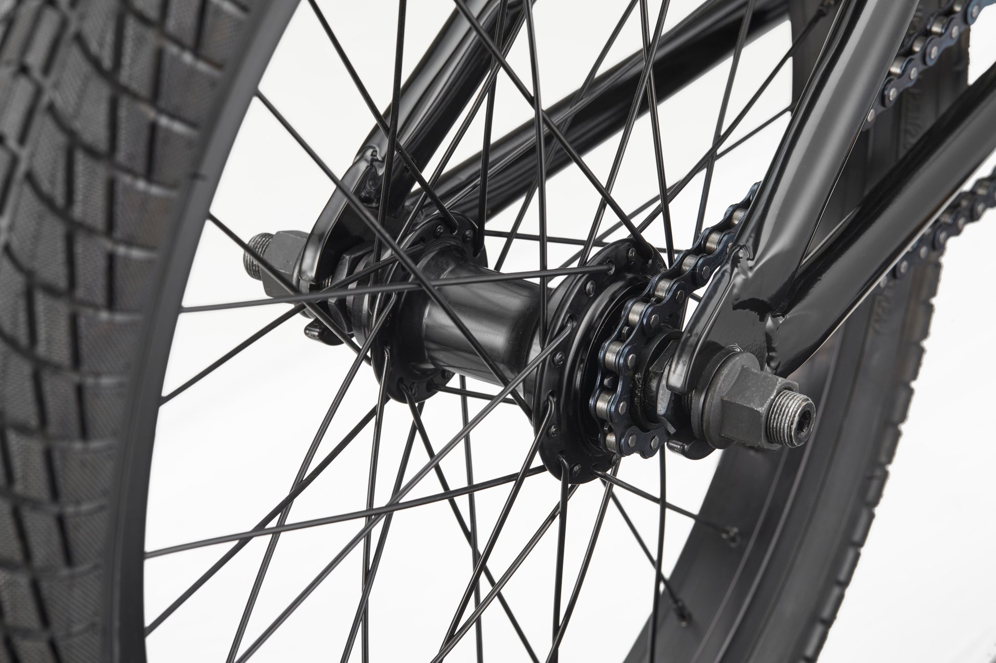 Close-up of Downtown 18 BMX wheel—black spokes, hub, chain, and tread—ideal for young riders against a white background.