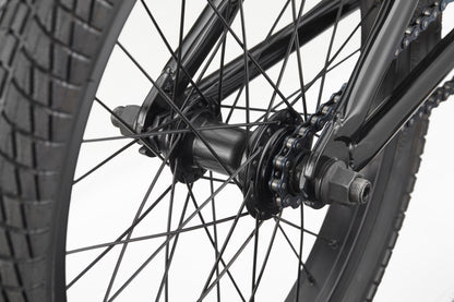 Close-up of Downtown 18 BMX wheel—black spokes, hub, chain, and tread—ideal for young riders against a white background.