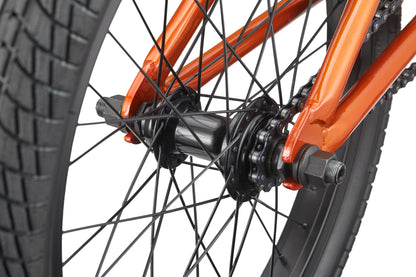 Close-up of the Downtown 18’s rear wheel hub, featuring black spokes, chain, and an orange frame—ideal for young riders.
