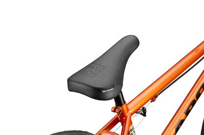 Close-up of a black BMX seat on an orange Downtown 20 bike frame, with part of the rear wheel visible.