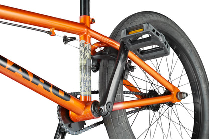 Close-up of the rear section of an orange Haro Downtown 20 BMX bike, showing the wheel, pedal, frame, chain, and seat post.