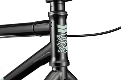 Close-up of a black Downtown 24 BMX frame with light blue logo and cables near handlebars, highlighting modern versatility.